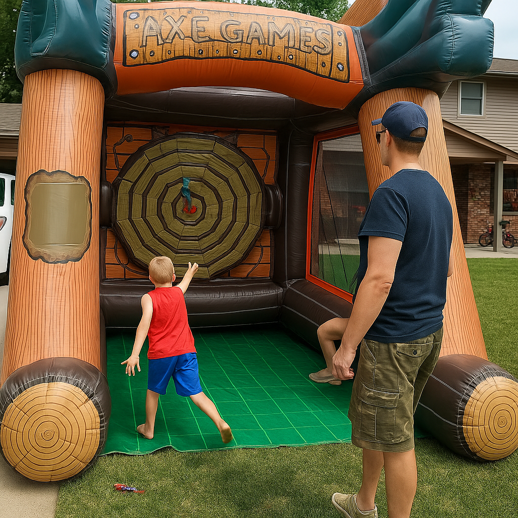 A young boy throws a foam axe at an inflatable target as an adult watches, both standing on a green mat in a backyard setting with a house in the background.