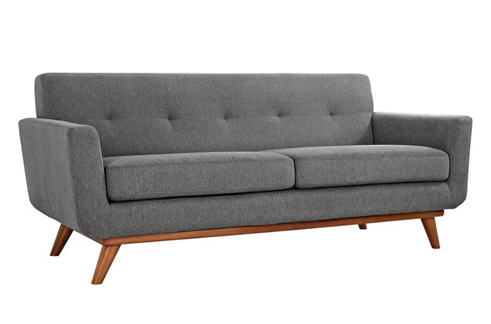 A modern grey fabric sofa with angled wooden legs and slightly angled armrests, featuring a tufted backrest and two seat cushions.