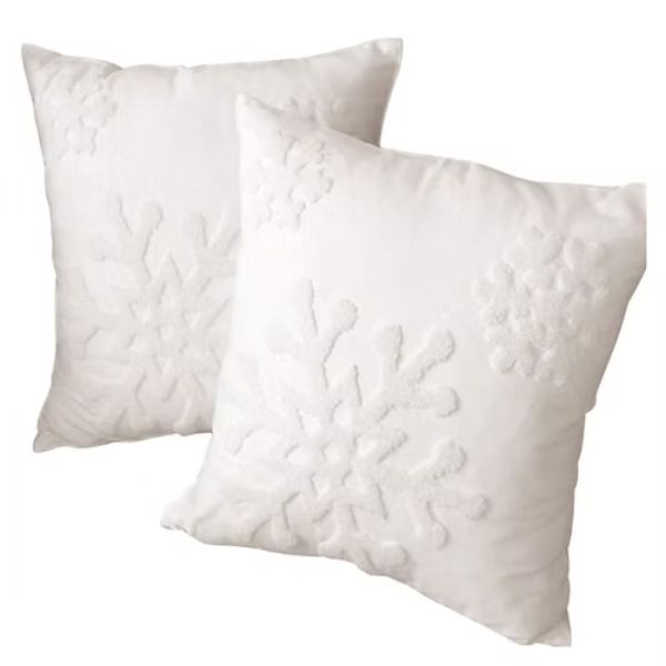 Two white throw pillows with textured snowflake patterns on the front, placed against a plain white background—a cozy touch to pair with rent tables, linens, and chairs for your holiday party.